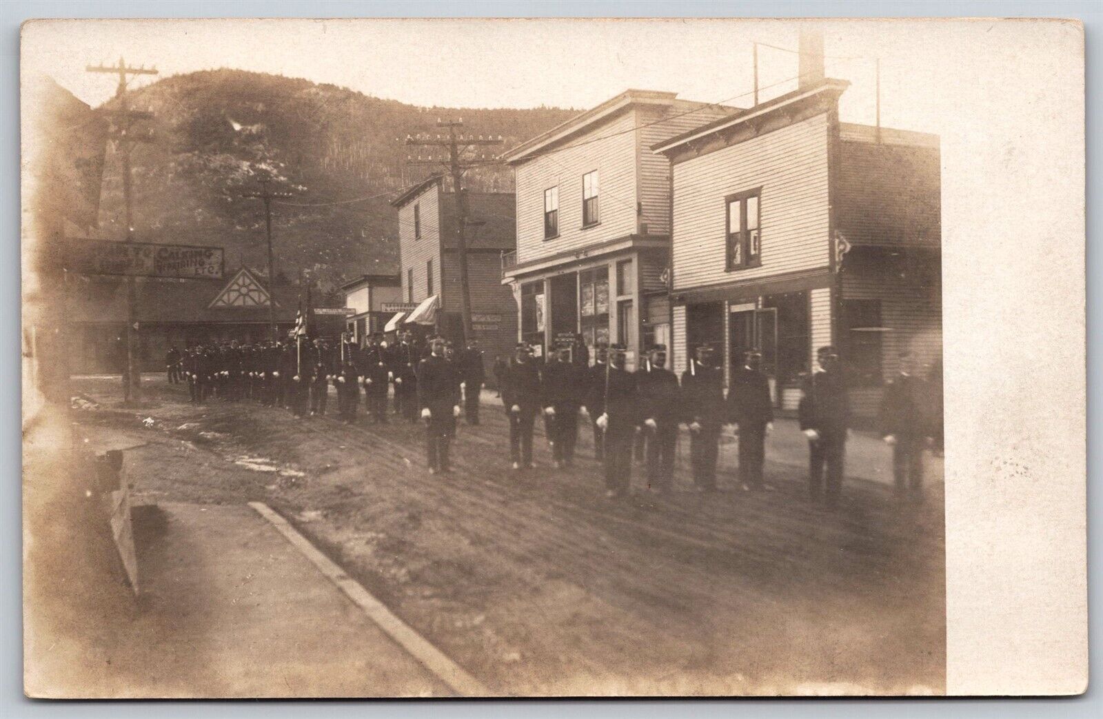 Postcard Military Soldiers Parade Rural Street Scene Shops Signs RPPC T112